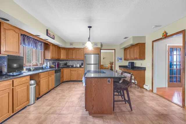 a kitchen with kitchen island granite countertop wooden cabinets and stainless steel appliances