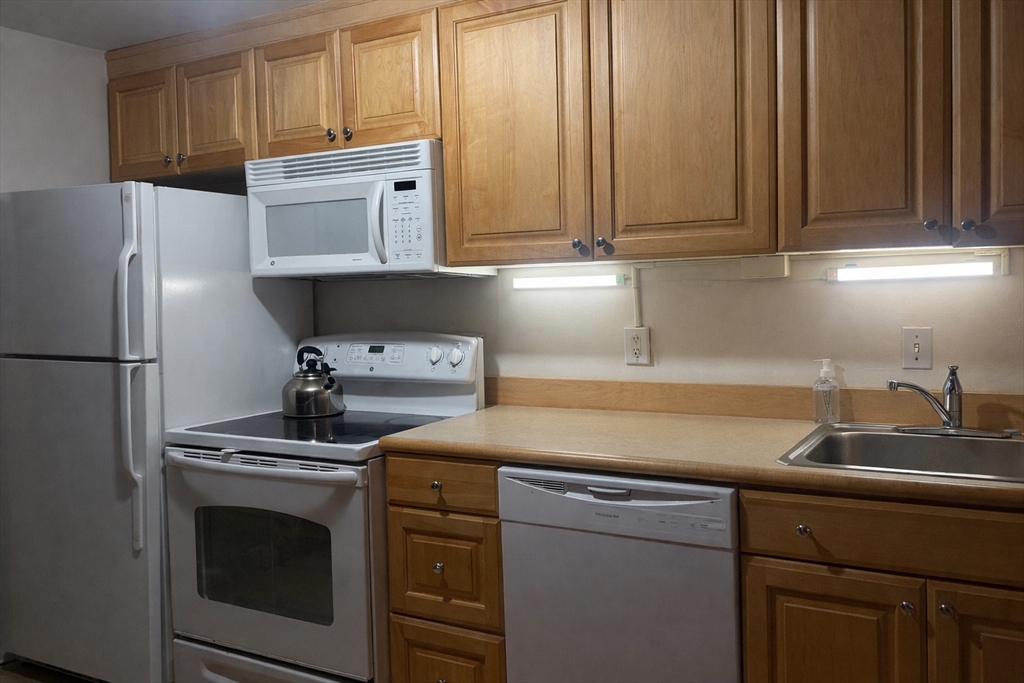 100 Marion Street, Unit B Brookline, MA 02446 - Photo 4 of 9 a kitchen with stainless steel appliances white cabinets and a sink