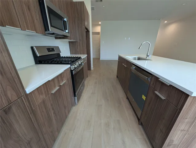 a kitchen with a sink a stove top oven and wooden floor
