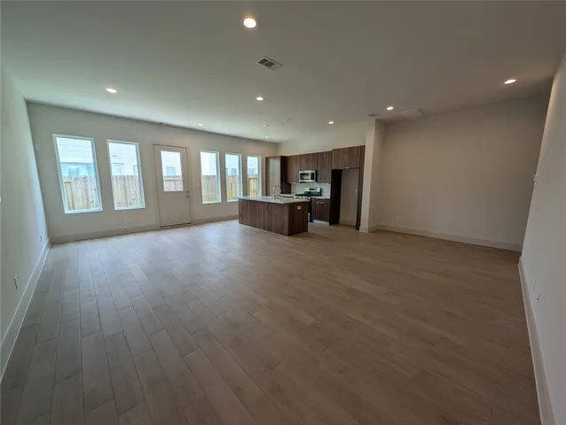 a view of empty room with wooden floor and windows