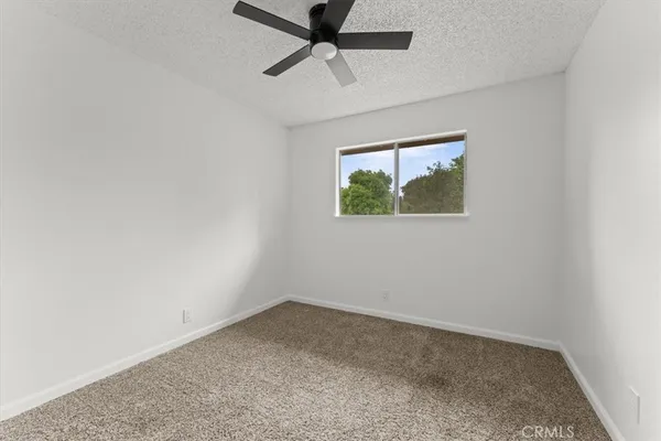 an empty room with a window and a ceiling fan
