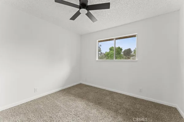 an empty room with a window and a ceiling fan