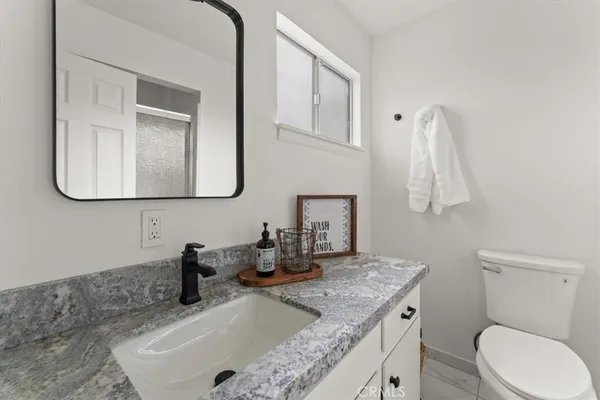 a bathroom with a granite countertop sink a toilet and mirror