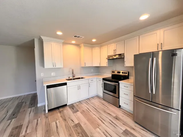 a kitchen with granite countertop a refrigerator stove top oven and sink