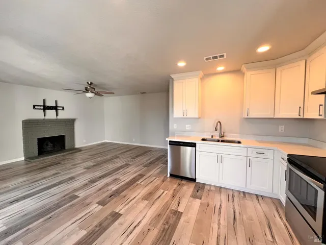 a kitchen with a sink dishwasher a fireplace with wooden cabinets and floor