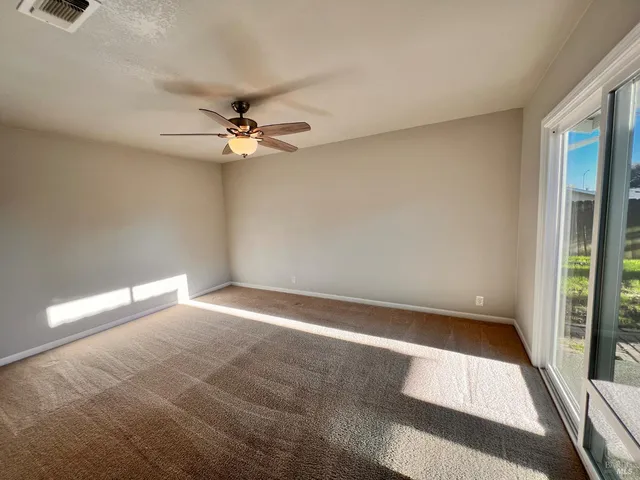 en empty room with windows and ceiling fan