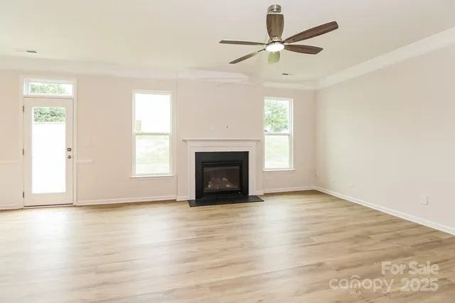 an empty room with wooden floor a ceiling fan and windows