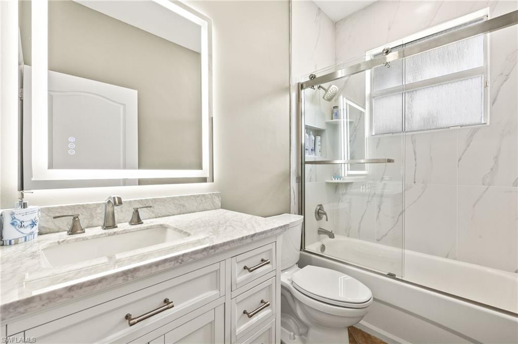 9890 Rookery Circle Estero, FL 33928 - Photo 19 of 26 a bathroom with a granite countertop sink a toilet and shower