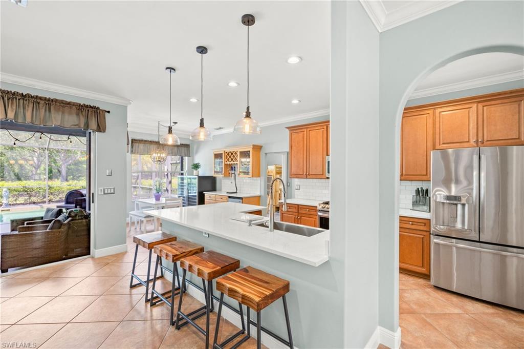 9890 Rookery Circle Estero, FL 33928 - Photo 8 of 26 a kitchen with stainless steel appliances granite countertop a refrigerator a sink a stove and white cabinets with wooden floor
