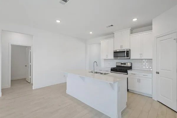 a kitchen with stainless steel appliances a stove a sink a refrigerator a microwave and cabinets
