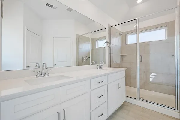 a bathroom with a double vanity sink mirror and shower