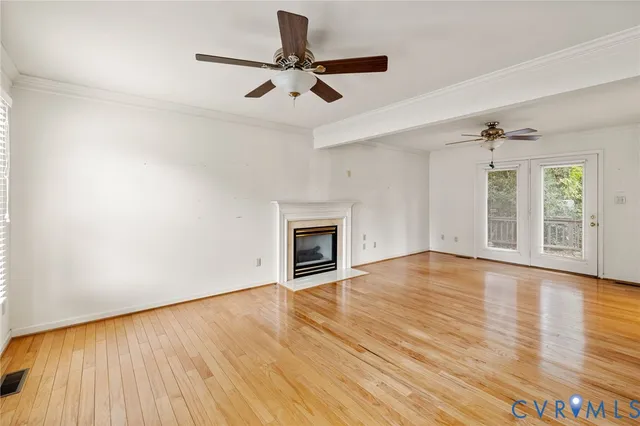 an empty room with wooden floor fireplace and windows