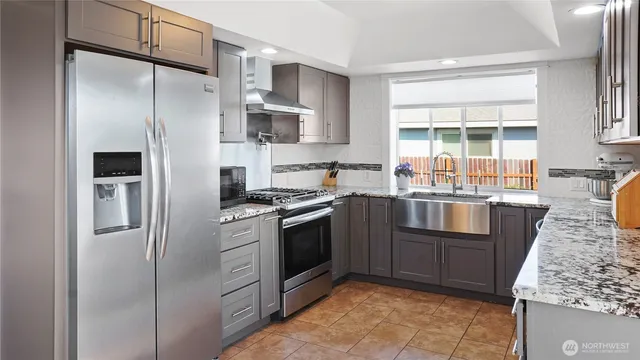 a kitchen with stainless steel appliances granite countertop a refrigerator stove and sink