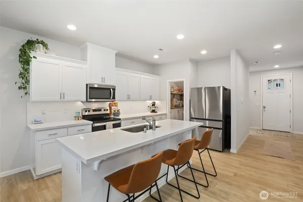 a kitchen with stainless steel appliances a stove a refrigerator a microwave oven with a dining table and chairs