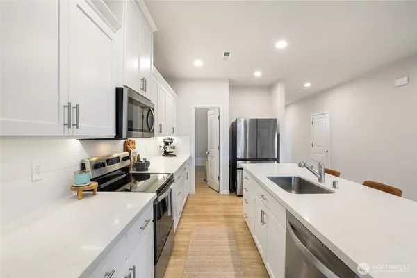 a kitchen with stainless steel appliances a sink a stove a refrigerator and cabinets