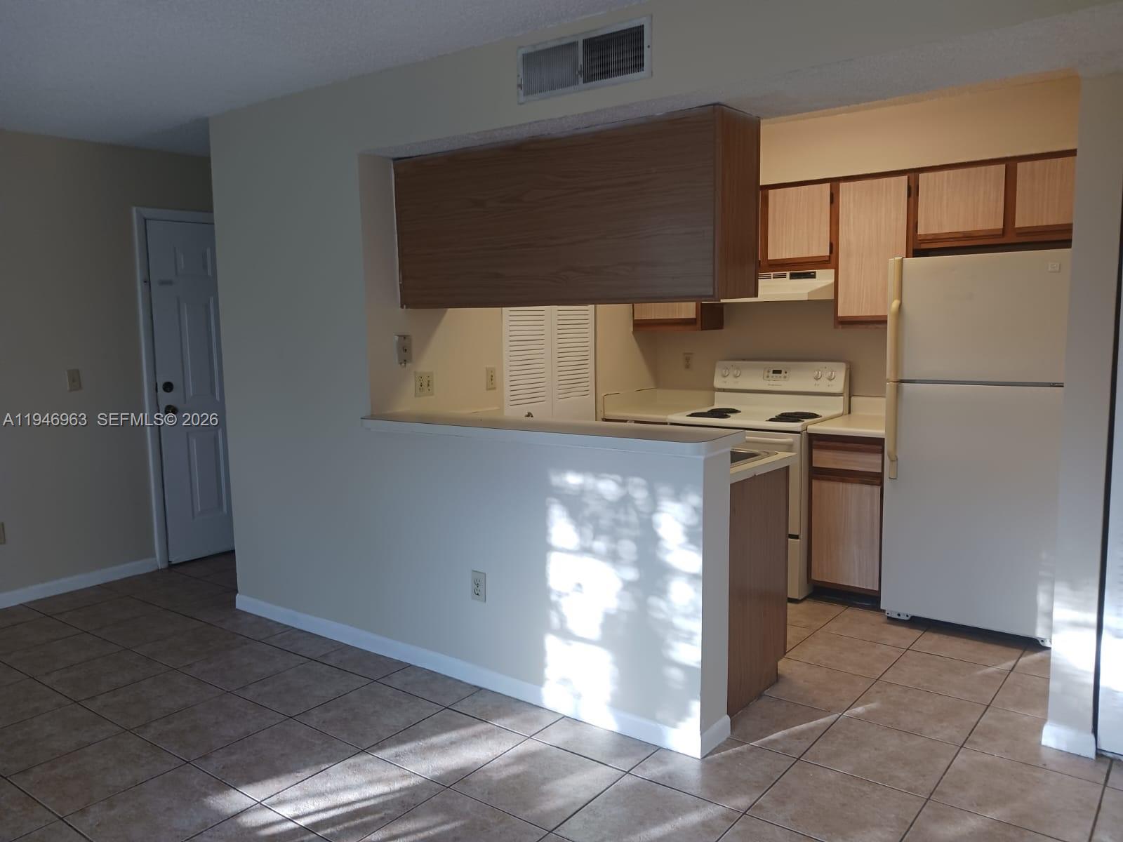 1239 Southwest 46th Avenue, Unit 903 Pompano Beach, FL 33069 - Photo 14 of 16 a kitchen with stainless steel appliances a refrigerator a sink and white cabinets