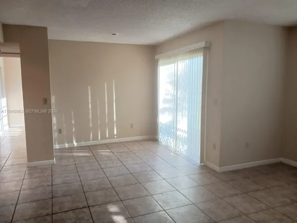 a view of an empty room with window and a bathroom