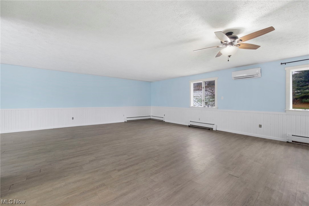 6322 Homeworth Road Homeworth, OH 44634 - Photo 17 of 36 Spare room with dark hardwood / wood-style floors, ceiling fan, a wall mounted AC, and a healthy amount of sunlight