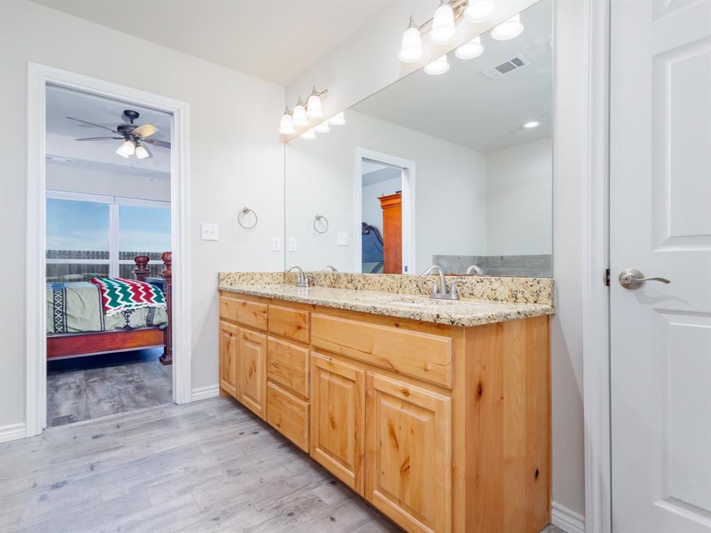 202 East Hall Court Early, TX 76802 - Photo 14 of 34 a bathroom with a granite countertop sink a toilet and a mirror