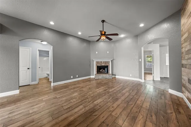 a view of empty room with wooden floor and ceiling fan