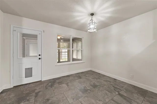 an empty room with chandelier and windows