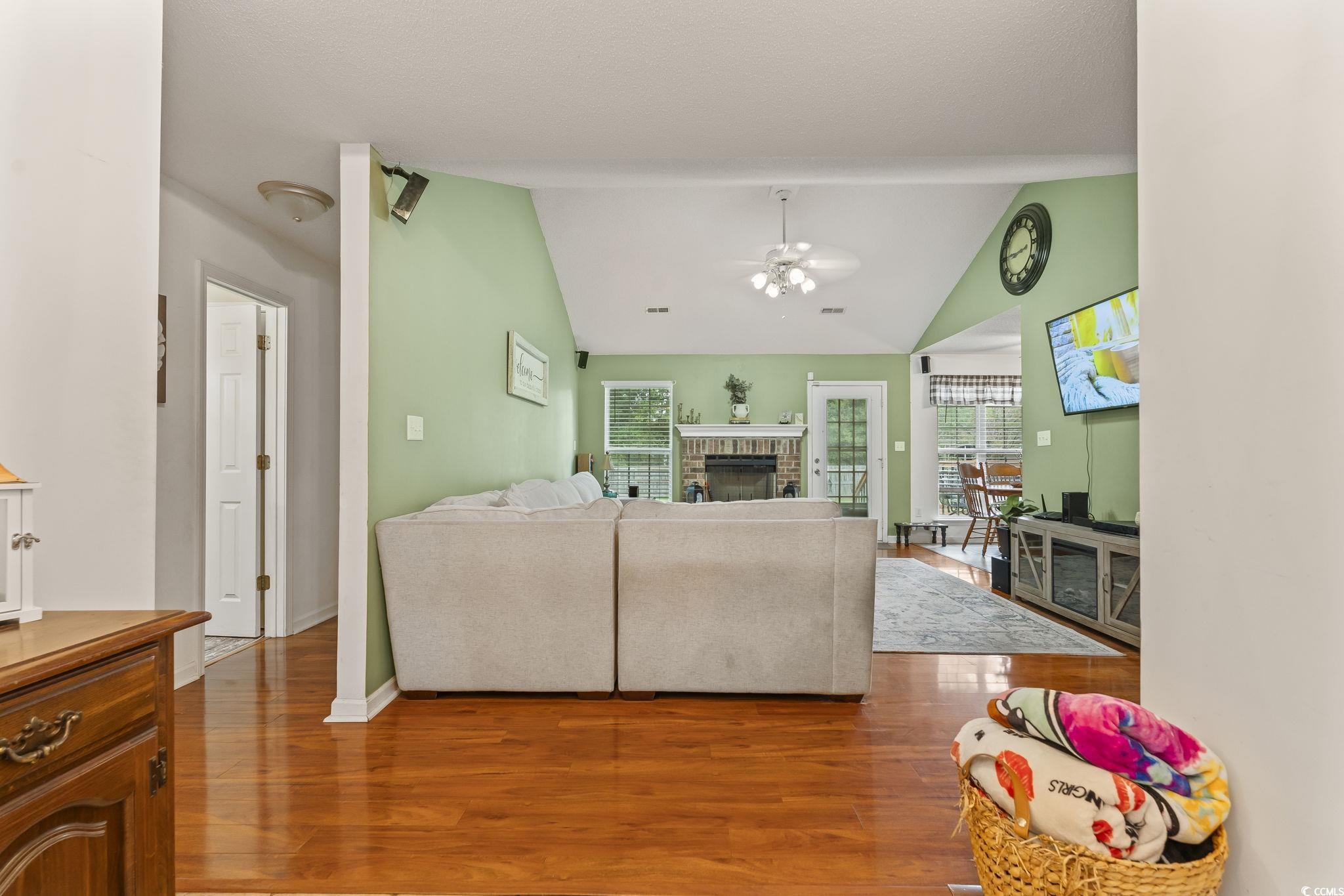 154 Hummingbird Court Myrtle Beach, SC 29579 - Photo 17 of 38 Living room with lofted ceiling, wood finished floors, a brick fireplace, and ceiling fan