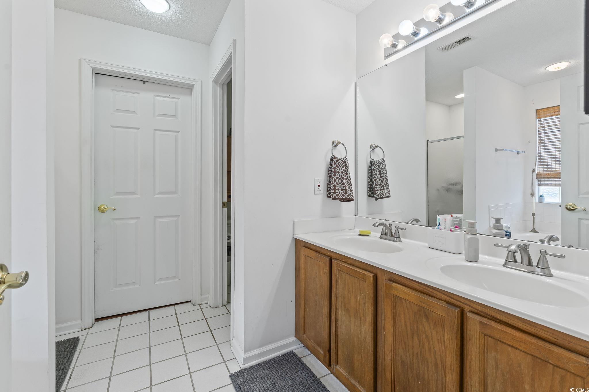 154 Hummingbird Court Myrtle Beach, SC 29579 - Photo 20 of 38 Bathroom with light tile patterned flooring, a stall shower, double vanity, and a textured ceiling
