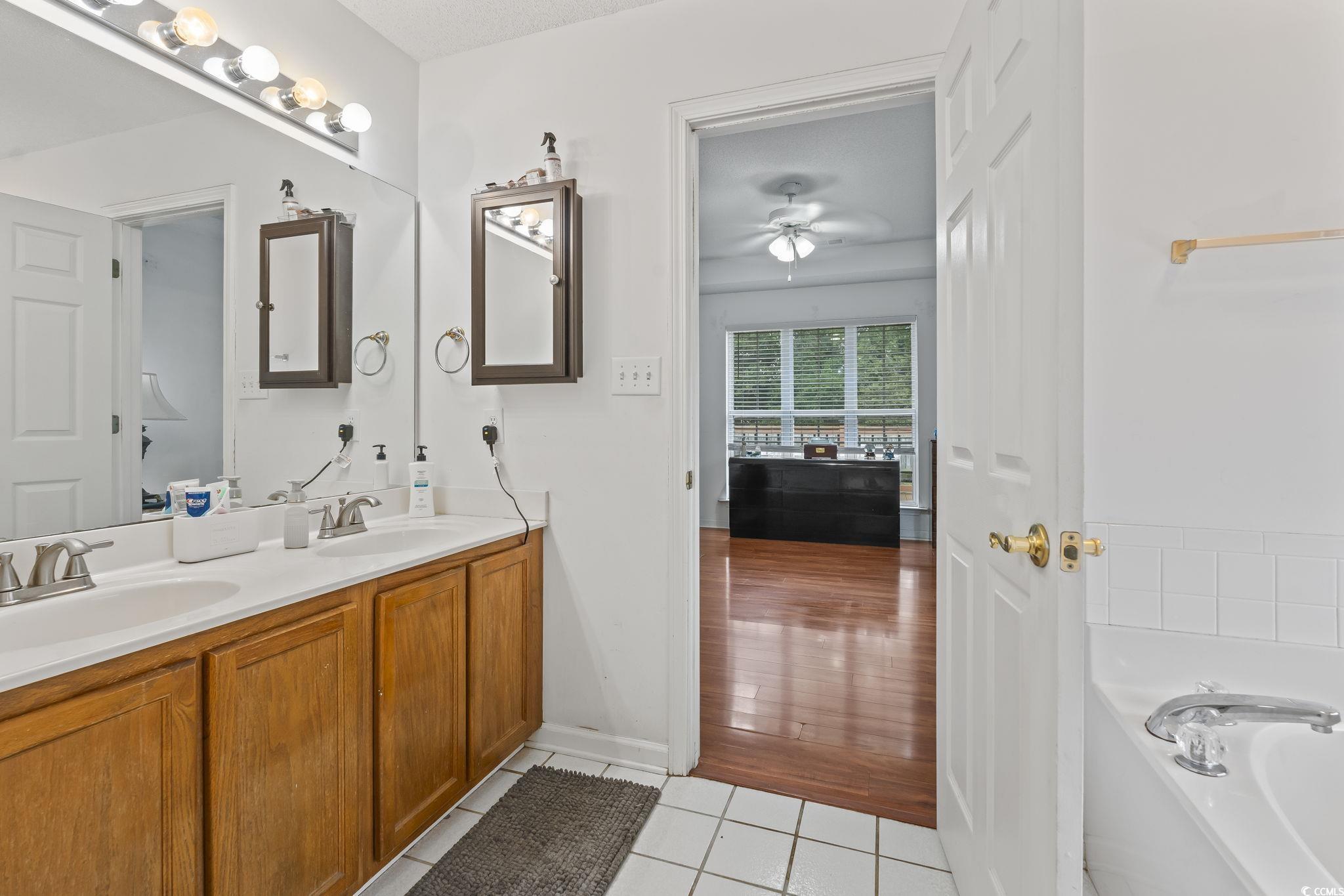 154 Hummingbird Court Myrtle Beach, SC 29579 - Photo 22 of 38 Bathroom featuring light tile patterned floors, double vanity, a bath, and a ceiling fan