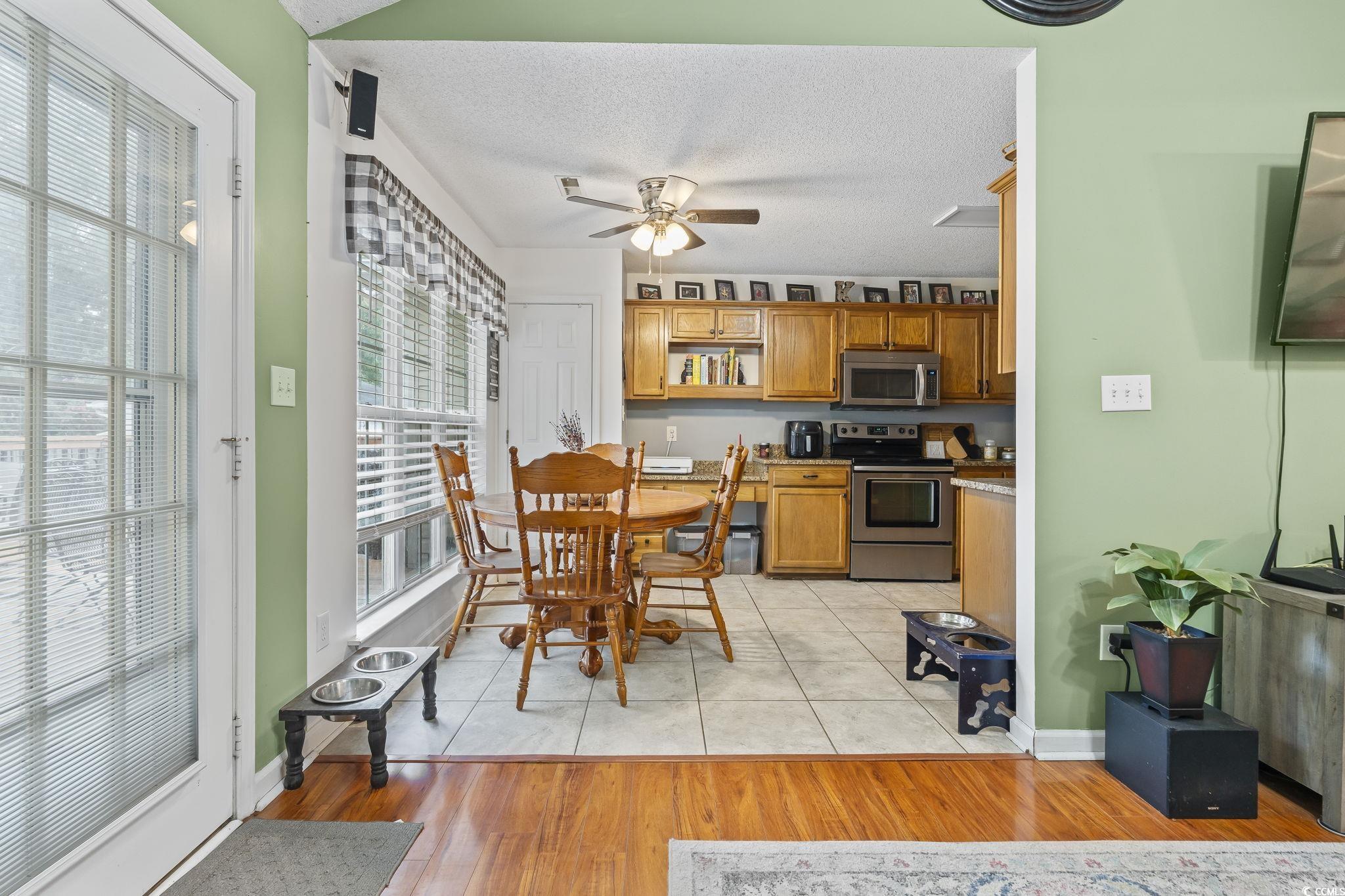 Dining area featuring a textured ceiling, light wood-style floors, and ceiling fan