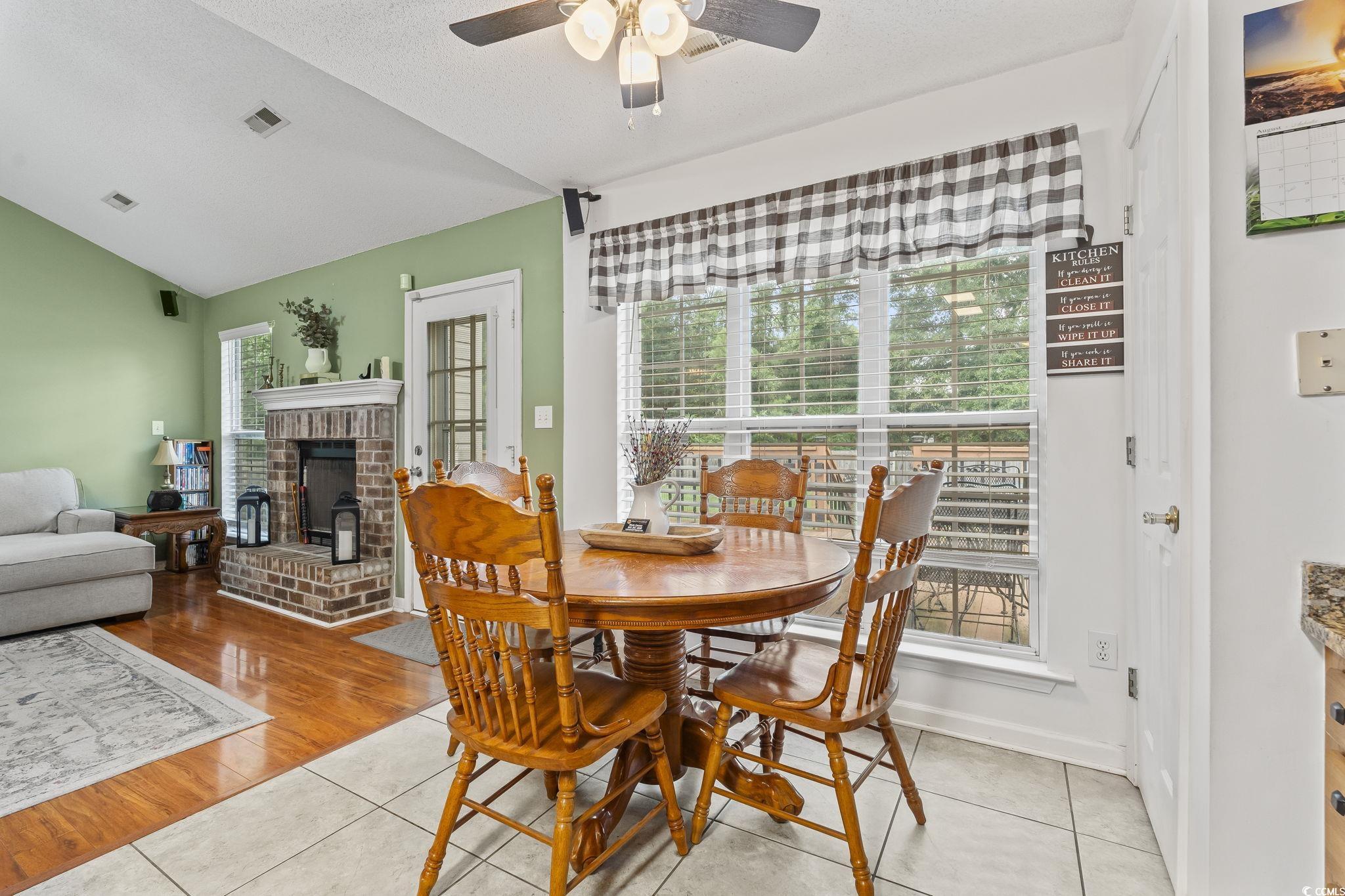154 Hummingbird Court Myrtle Beach, SC 29579 - Photo 8 of 38 Dining area with lofted ceiling, light tile patterned floors, a textured ceiling, a fireplace, and a ceiling fan