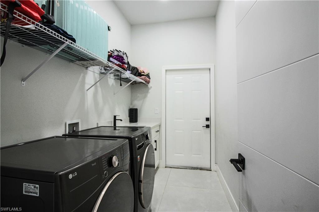 3902 4th Street Southwest Lehigh Acres, FL 33976 - Photo 16 of 34 White tile flooring, built-in wire shelving, white wall paneling, counter space, and a sink with a black faucet