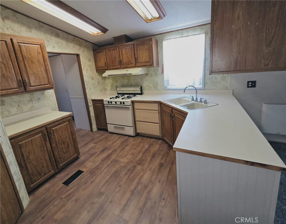49645 3 Points Road Lancaster, CA 93536 - Photo 14 of 40 a kitchen with a sink a stove wooden floor and a refrigerator