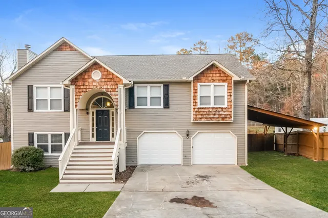 a view of a white house with a small yard and large trees