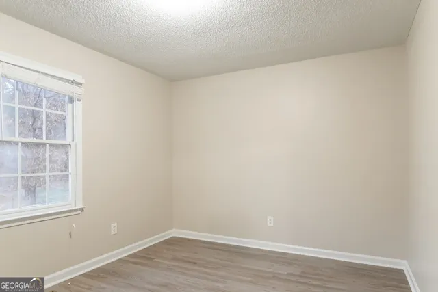 a view of an empty room with wooden floor and windows