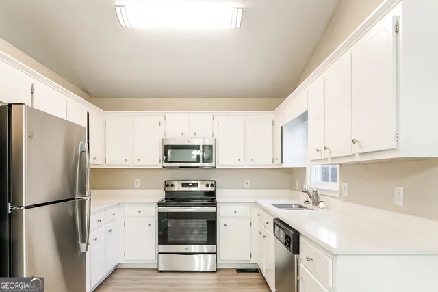 a kitchen with stainless steel appliances a refrigerator sink and white cabinets