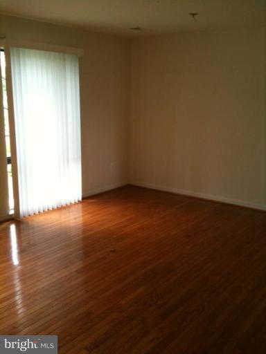 7922 Spring Forest Court, Unit 4A Springfield, VA 22152 - Photo 11 of 12 an empty room with wooden floor and windows with curtains