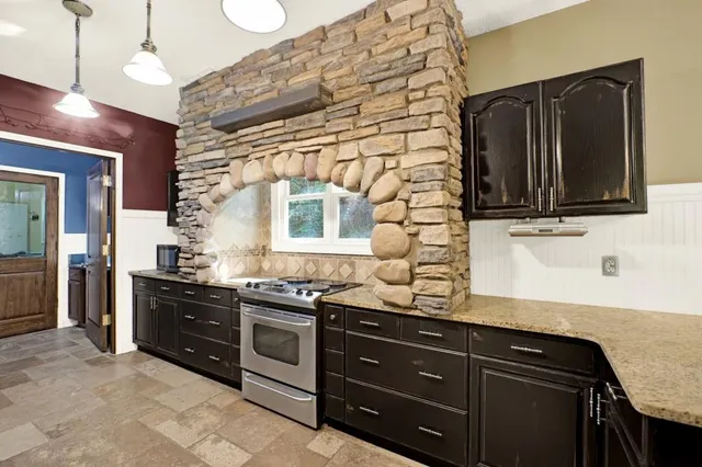 a kitchen with stainless steel appliances granite countertop a refrigerator a stove and a sink
