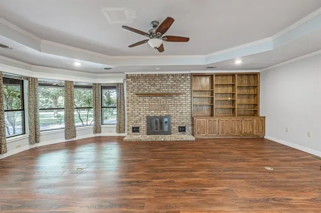 a view of an empty room with wooden floor and a fireplace