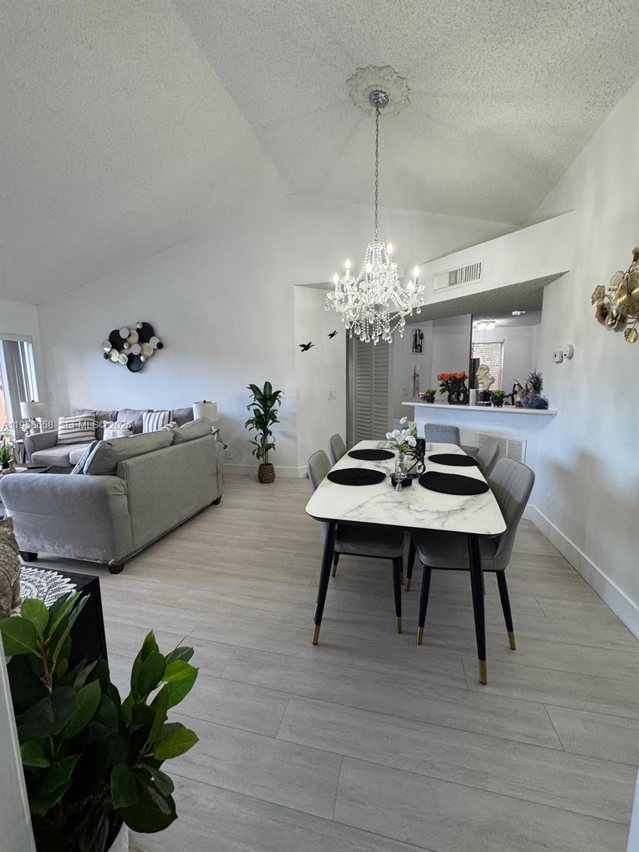 8801 Wiles Road, Unit 308 Coral Springs, FL 33067 - Photo 12 of 16 a living room with furniture a chandelier and a table