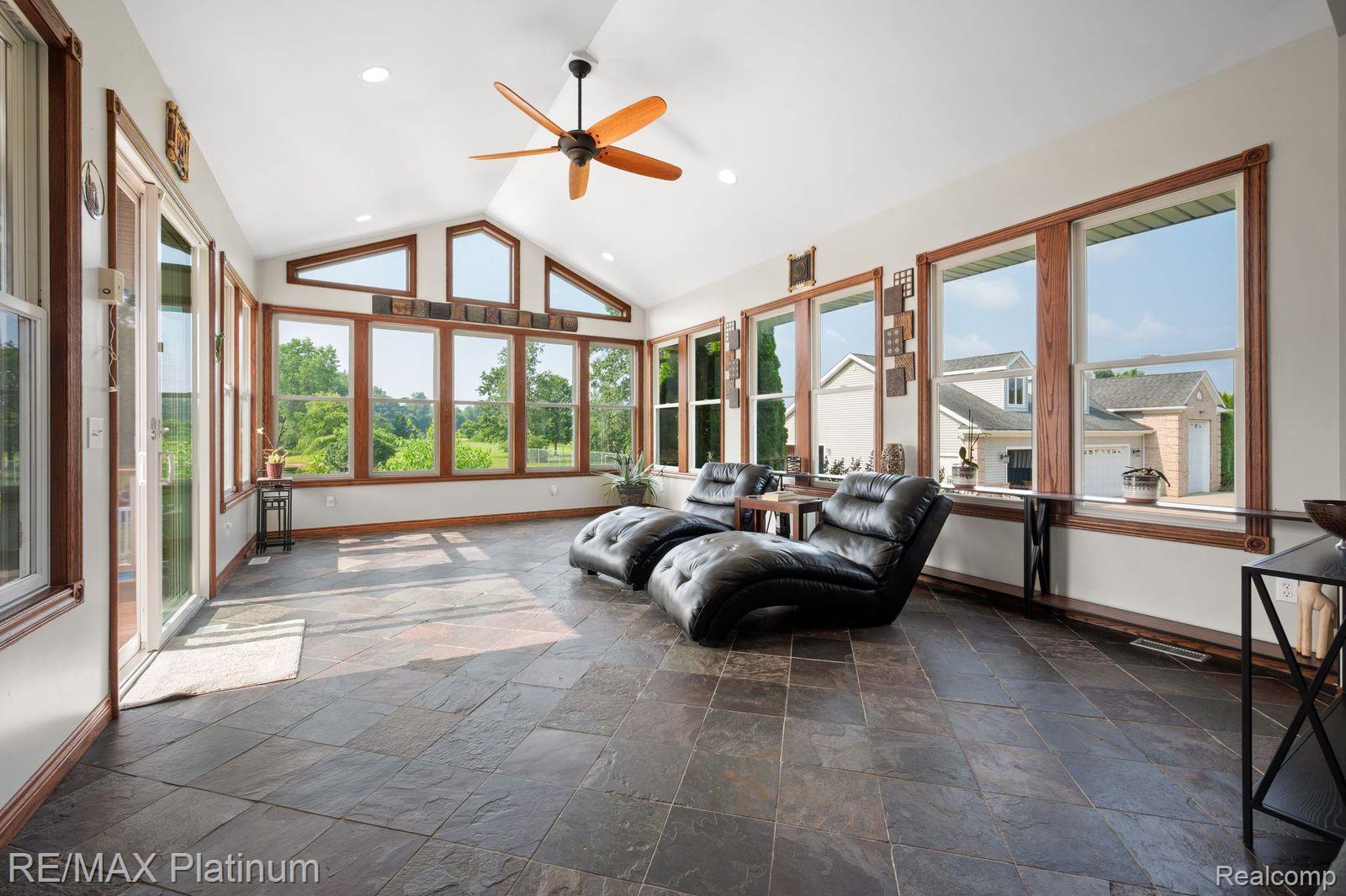 8922 McClements Road Brighton, MI 48114 - Photo 9 of 65 Sunroom featuring a vaulted ceiling with a ceiling fan, stone tile flooring, and extensive natural light through multiple windows with wood trim