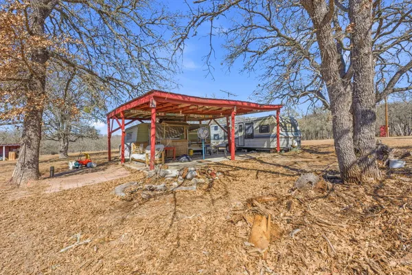 a view of a house with a dirt yard and a large tree