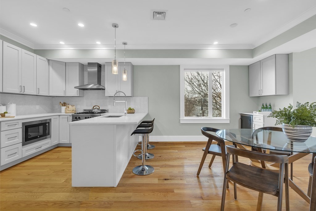 17 Vinton Street, Unit PH Boston, MA 02127 - Photo 14 of 36 a kitchen with stainless steel appliances granite countertop a stove top oven a sink dishwasher a dining table and chairs with wooden floor