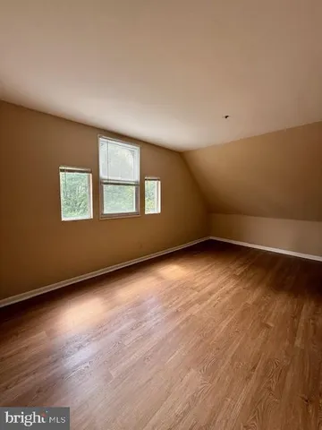 a view of an empty room with wooden floor and window