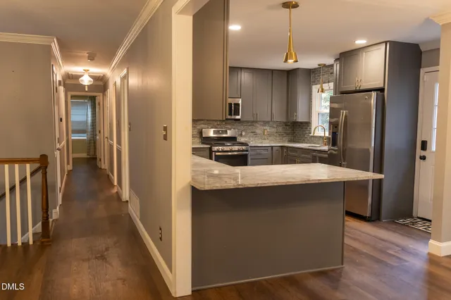 a kitchen with stainless steel appliances granite countertop a refrigerator a stove and a sink