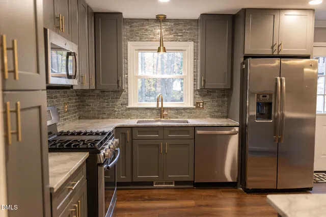 a kitchen with stainless steel appliances granite countertop a sink a stove a refrigerator and island