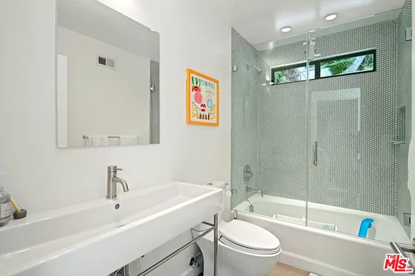 a bathroom with a bathtub shower sink vanity mirror and toilet