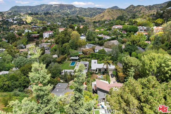 an aerial view of residential houses with outdoor space and trees