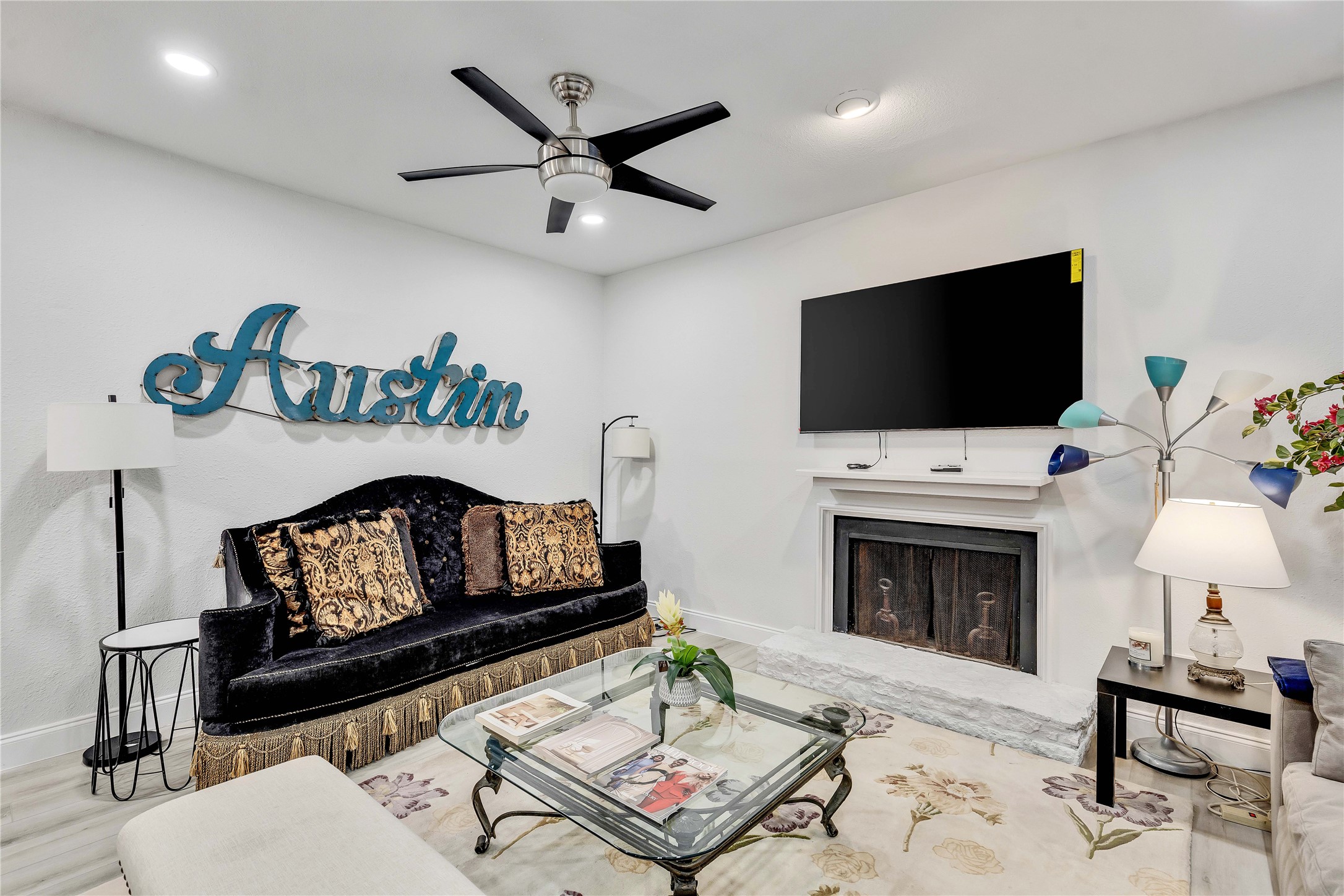2529 Rio Grande Street, Unit 56 Austin, TX 78705 - Photo 7 of 16 Living room with a fireplace with raised hearth, wood finished floors, baseboards, and a ceiling fan