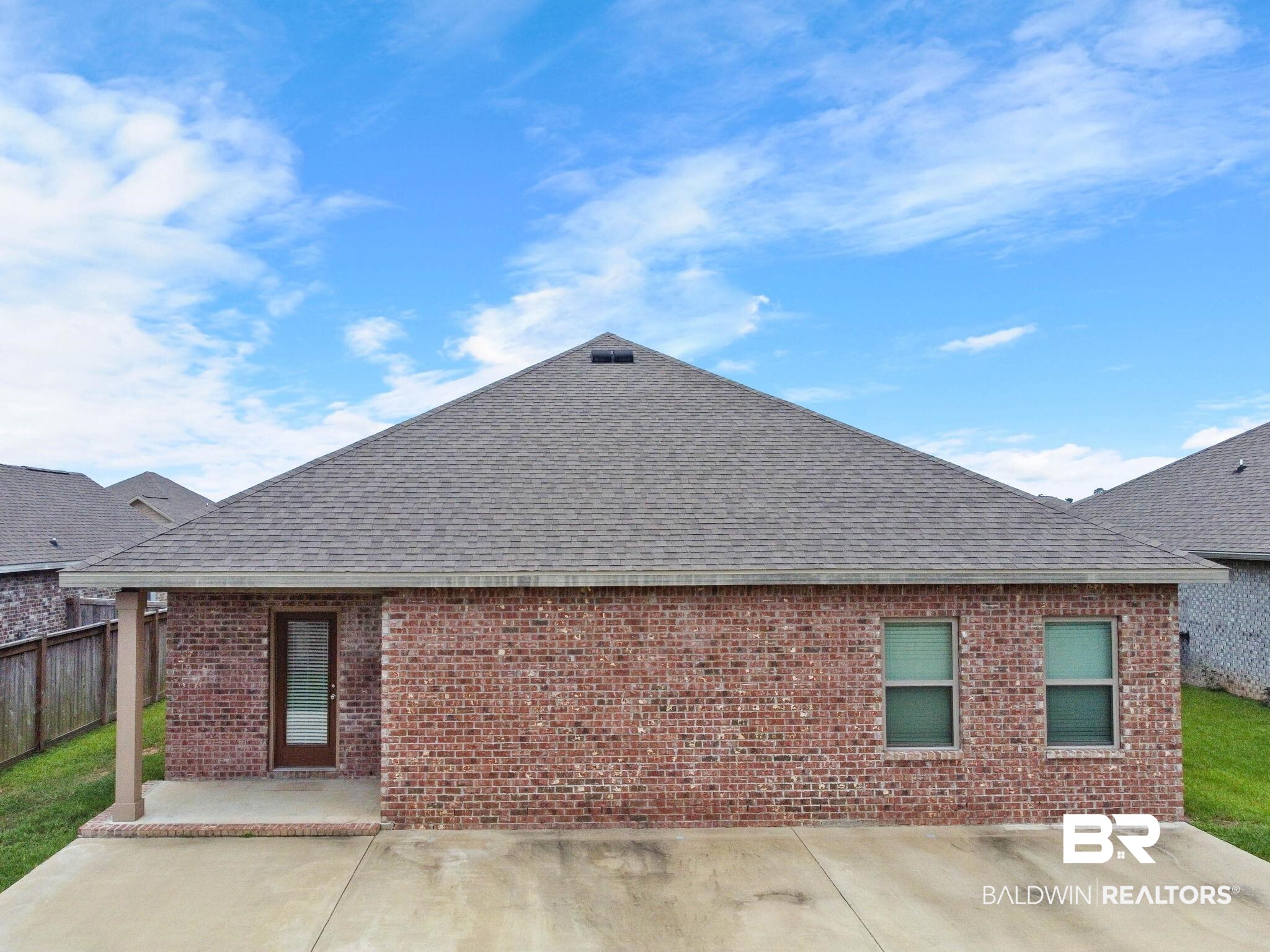 1710 Grouse Street Foley, AL 36535 - Photo 73 of 76 Brick exterior with a gray shingle roof, two double-hung windows, and a covered concrete patio