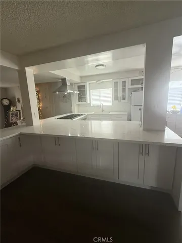 a view of a refrigerator in kitchen and an empty room